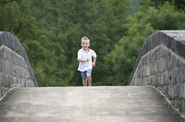 summer time : little boy running on a bridge