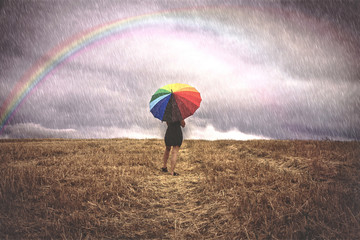 Mujer con paraguas de colores bajo la lluvia en el campo