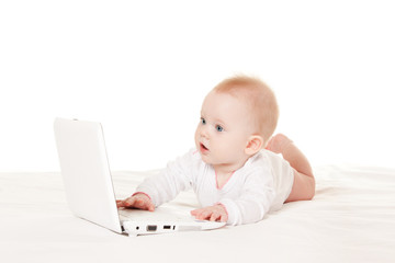 Cute baby with laptop on the white bed