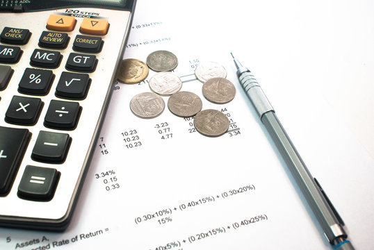 coins and calculator and pen on financial figure