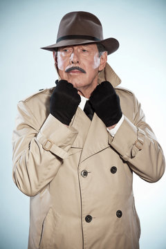 Vintage detective man with mustache and hat. Wearing raincoat. S