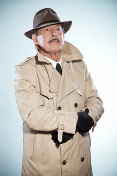 Vintage detective man with mustache and hat. Wearing raincoat. S