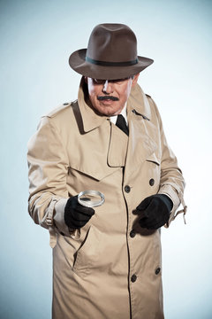 Retro detective man with mustache and hat. Holding magnifying gl