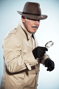 Retro detective man with mustache and hat. Holding magnifying gl