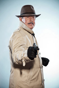 Vintage detective with mustache and hat. Holding gun. Studio sho