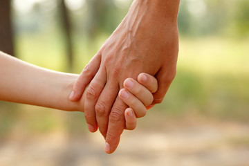 mother's hand lead her child in forest, trust family concept