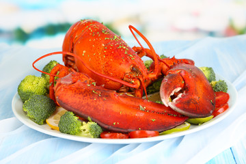 Red lobster on platter with vegetables on table close-up