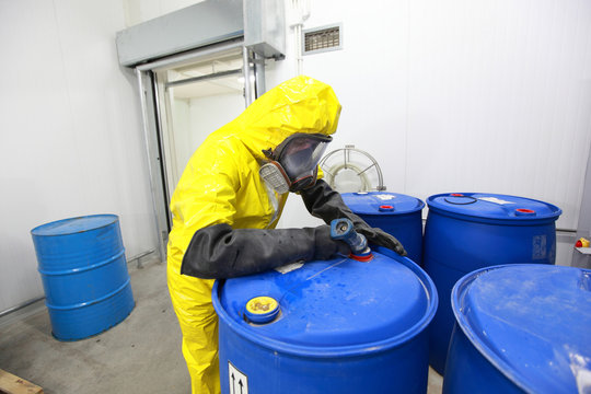 Professional in uniform filling barrels with chemicals