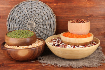 Different kinds of beans in bowls on wooden background