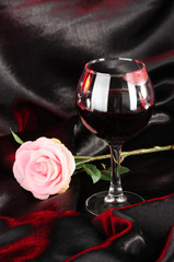 Glass of wine with lipstick imprint on black satin background