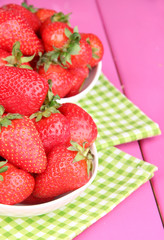 Fototapeta na wymiar Fresh strawberry in bowl on pink wooden background
