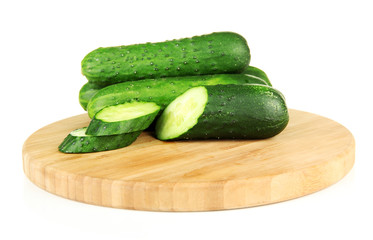 Tasty green cucumbers on wooden cutting board, isolated on