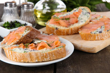 Fish sandwiches on cutting board and plate on wooden table