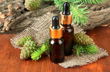 Bottles of fir tree oil and green cones on wooden table