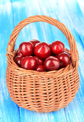 Cherry berries in wicker basket on wooden table close-up