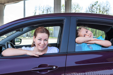 Caucasians mother and young daughter look out from car windows
