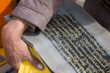 Old Tibetan language on old paper and the hand of a monk