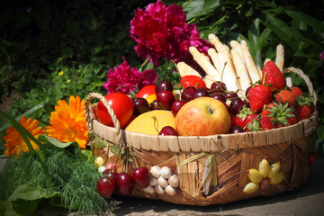 Korb mit Obst und Gemüse vor Pfingstrosen