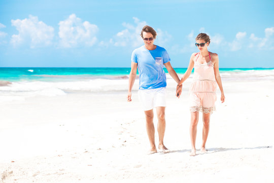 Young happy couple walking on beach smiling. Tulum, Mexico