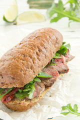 Bun with grilled roast beef and arugula.