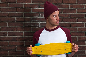 Hip cool urban fashion skateboarder with woolen hat posing in fr
