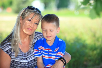 Happy family mother and son on bench in park