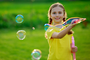 Summer joy, young girl playing with soap bubbles