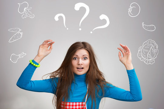 Confused young housewife with the drawn vegetables