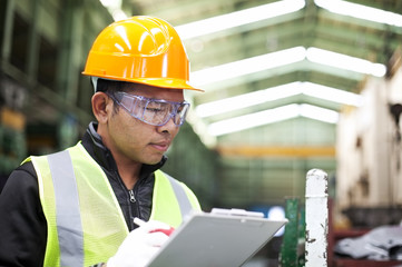 Factory worker writing on clipboard