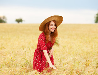 Redhead girl in red dress at wheat field