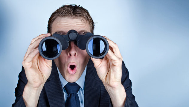 Businessman looking through field glasses or binoculars