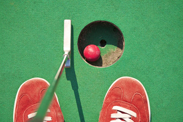 Close-up of miniature golf hole with bat and ball - 53699063