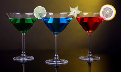 Alcoholic cocktails in martini glasses on dark yellow