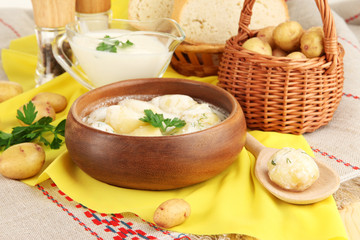 Tender young potatoes with sour cream and herbs in wooden bowl