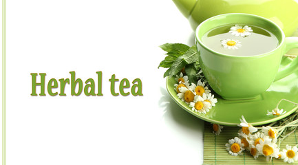 Cup and teapot of herbal tea with wild chamomiles and mint,