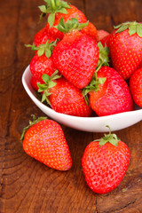 Fresh strawberry in bowl on wooden background