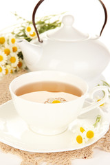 Cup of herbal tea with camomiles close up