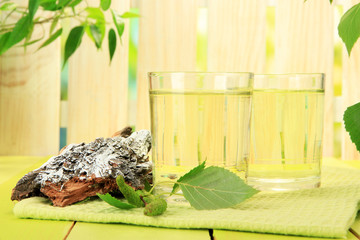 Glasses of birch sap on green wooden table