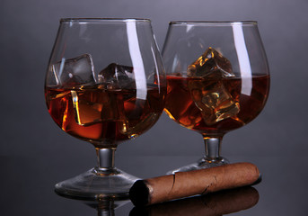 Brandy glasses with ice on grey background