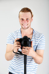 Obraz premium Handsome photographer with camera on monopod, on gray