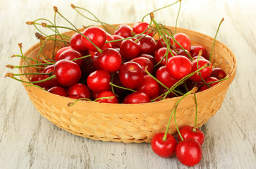 Fototapeta na wymiar Cherry berries in wicker basket on wooden table close up