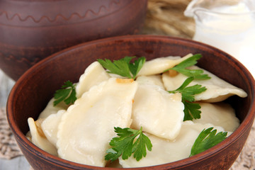 Tasty dumplings with fried onion on brown bowl, close-up