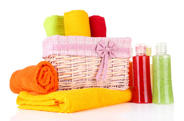 Colorful towels in basket and cosmetics bottles, isolated