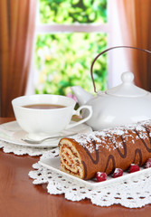 Sweet roll with cup of tea on table in room