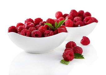 Ripe sweet raspberries in bowls, isolated on white