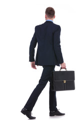 back of a business man with suitcase walking away