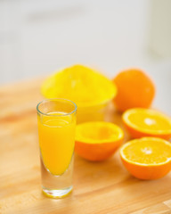 Closeup on glass of orange juice and oranges on cutting board