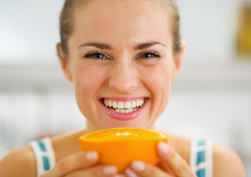 Smiling young woman holding orange slice