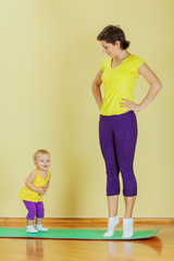 Mother do phisical exercises with her daughter at home