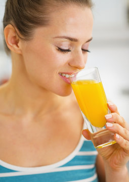 Portrait of happy young woman drinking fresh orange juice